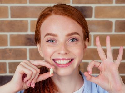 woman smiling with a tooth in her hand